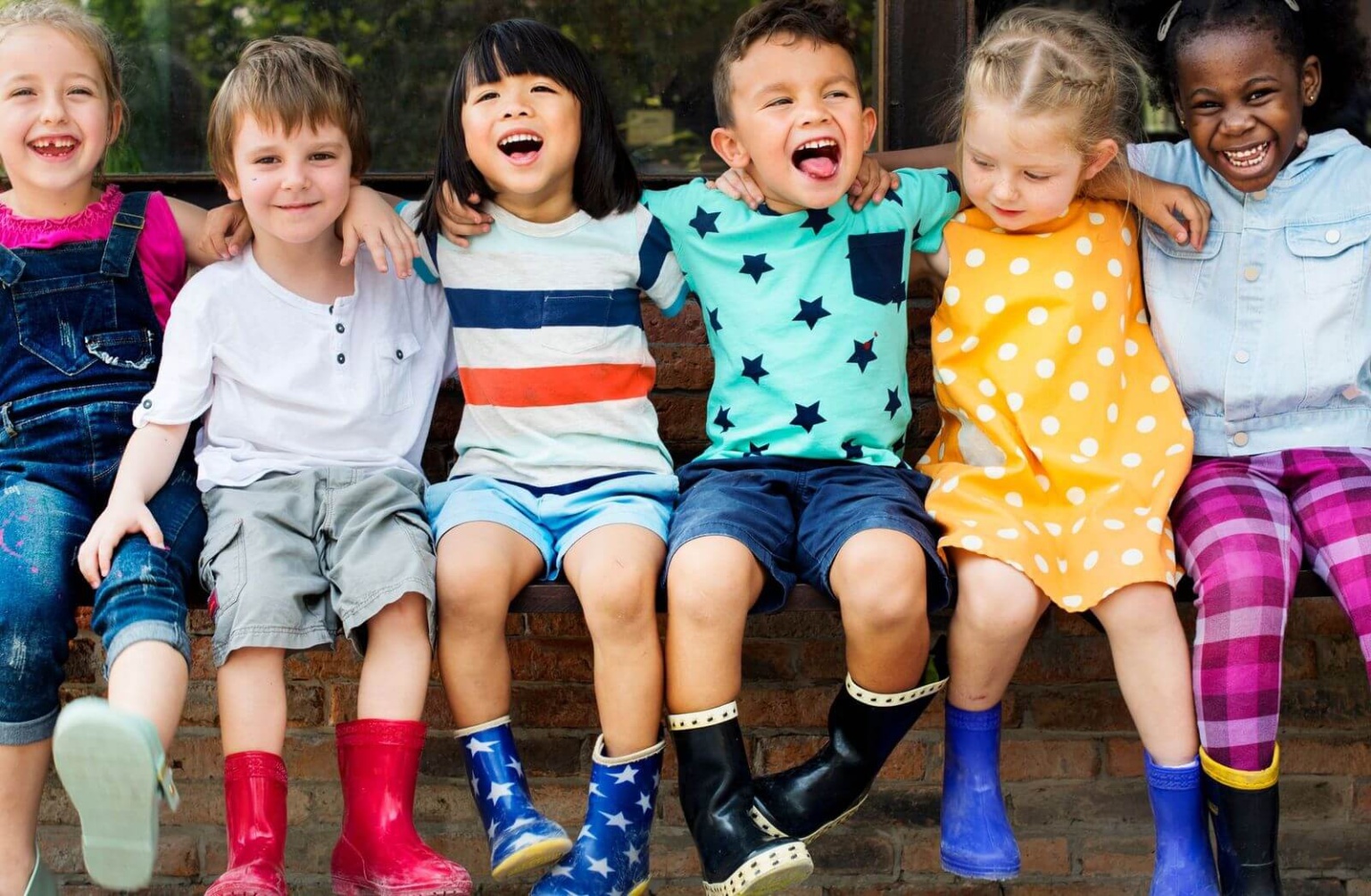 Children With Arms Around Each Other Sitting In A Childcare Centre